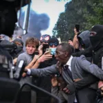 En uno de los momentos más tensos de la manifestación, el alcalde se colocó físicamente entre los estudiantes y agentes antidisturbios. En las imágenes que se difundieron posteriormente aparece con los brazos extendidos mientras intenta contener el avance de los policías y pide que se detengan - Foto: X/@Complex